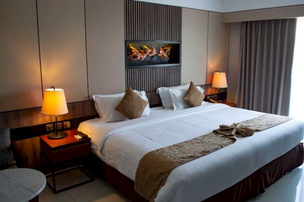 A hotel room with a large bed, two side lamps, decorative pillows, and a modern wall feature above the headboard.