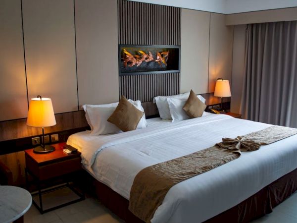 A hotel room with a large bed, two side lamps, decorative pillows, and a modern wall feature above the headboard.
