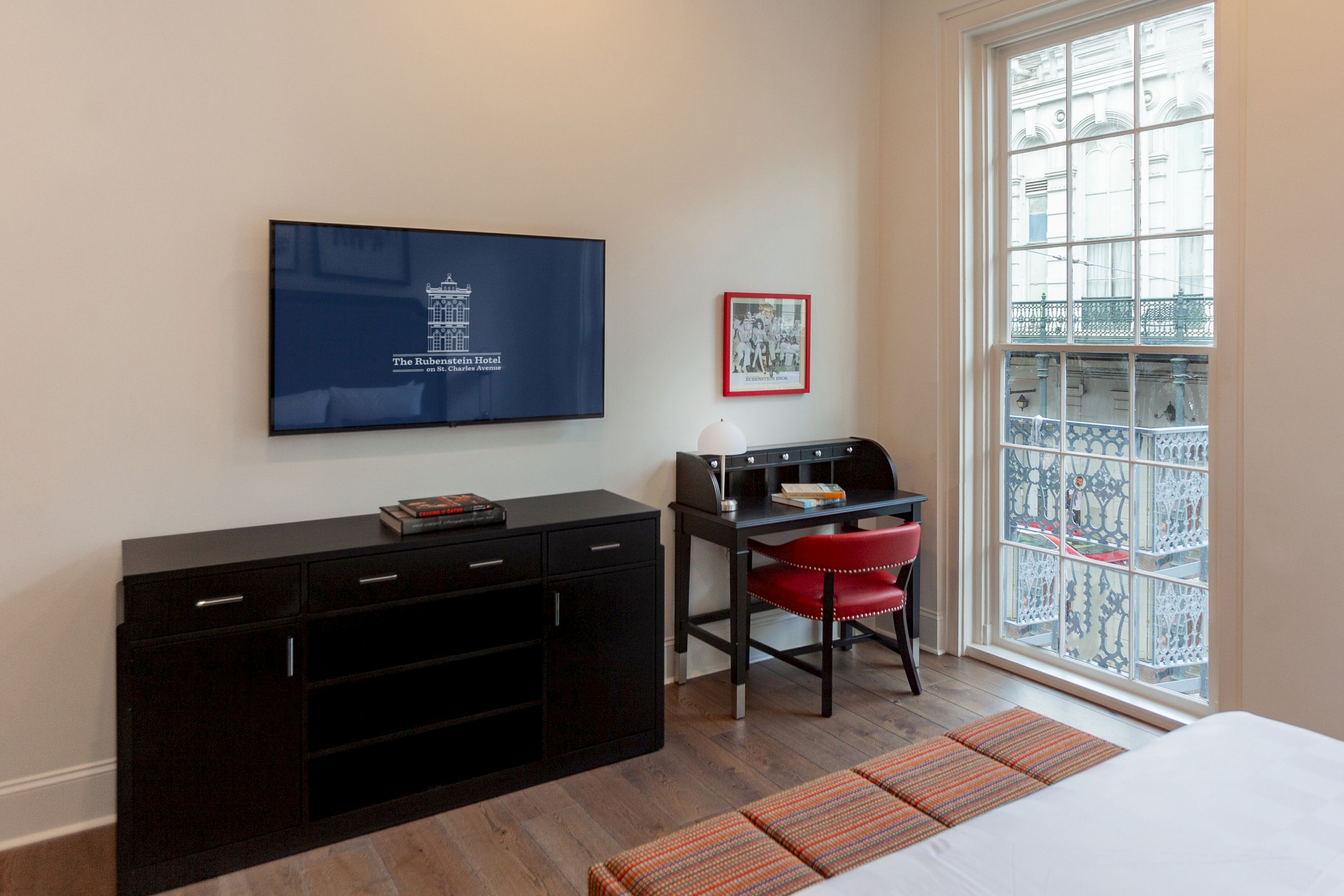 A hotel room with a desk, TV, and window