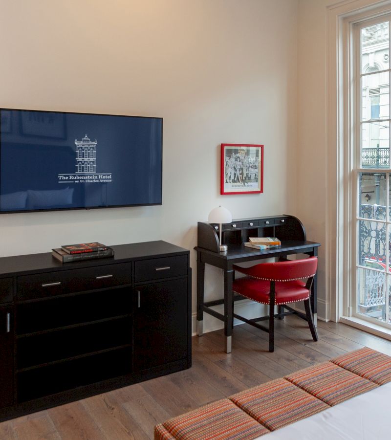 A hotel room with a desk, TV, and window