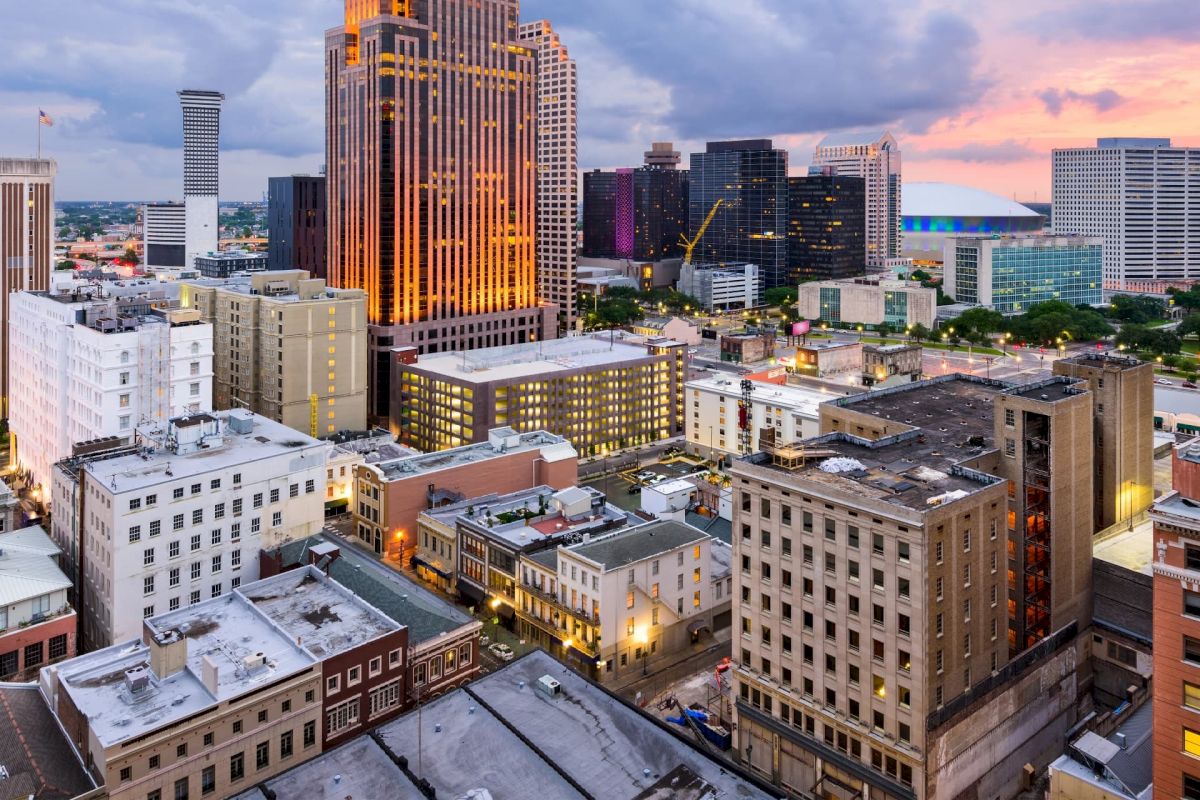 A cityscape at sunset with many buildings and a cloudy sky.