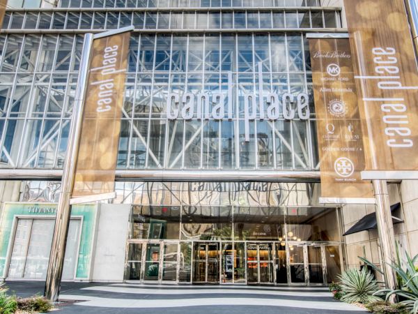 The image shows the entrance of a shopping center named Canal Place, with large glass windows and decorative banners.