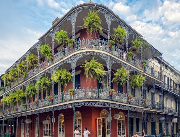 A three-story building with ornate ironwork balconies and palm trees