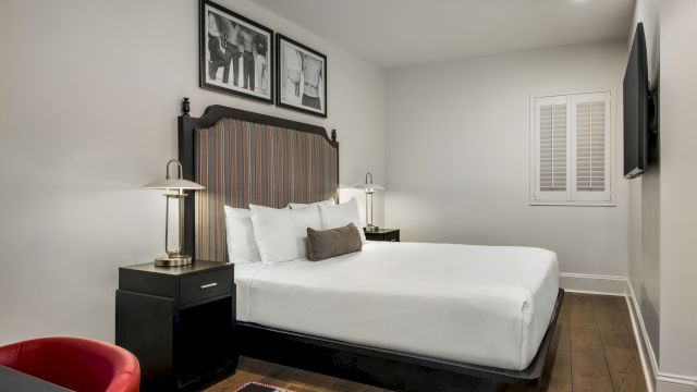 A hotel room with a bed, nightstand, lamp, TV, and chair.
