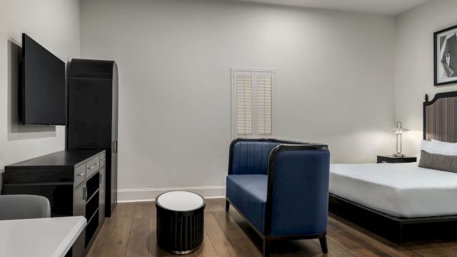 A hotel room with a bed, TV, sofa, and table.