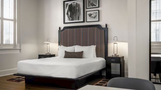 A hotel room with a large bed, two nightstands, and a chair