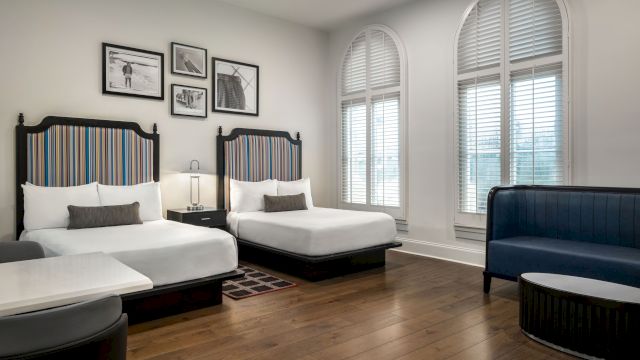 A hotel room with two beds, a blue sofa, and a coffee table.