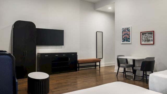 A wide view of a hotel room with a bed, TV, table, and chairs.