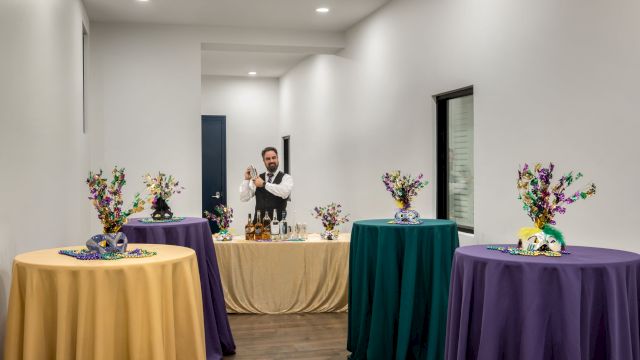 a bar with a bartender and several tables with colorful tablecloths