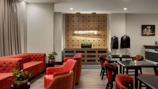 A lounge with red chairs and sofa, tables, and plants.