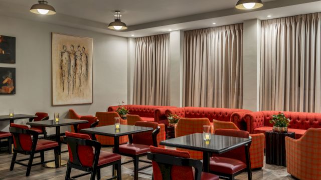 A dining area with red booths and chairs, tables, and artwork on the walls.
