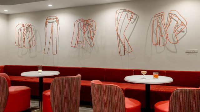 A modern lounge with red seating, white tables, and artistic wall decor.
