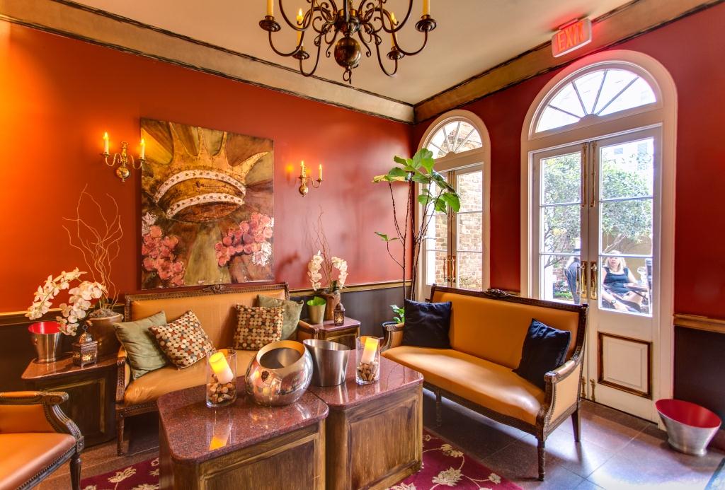 A luxurious lounge with red walls, a chandelier, and comfortable seating.